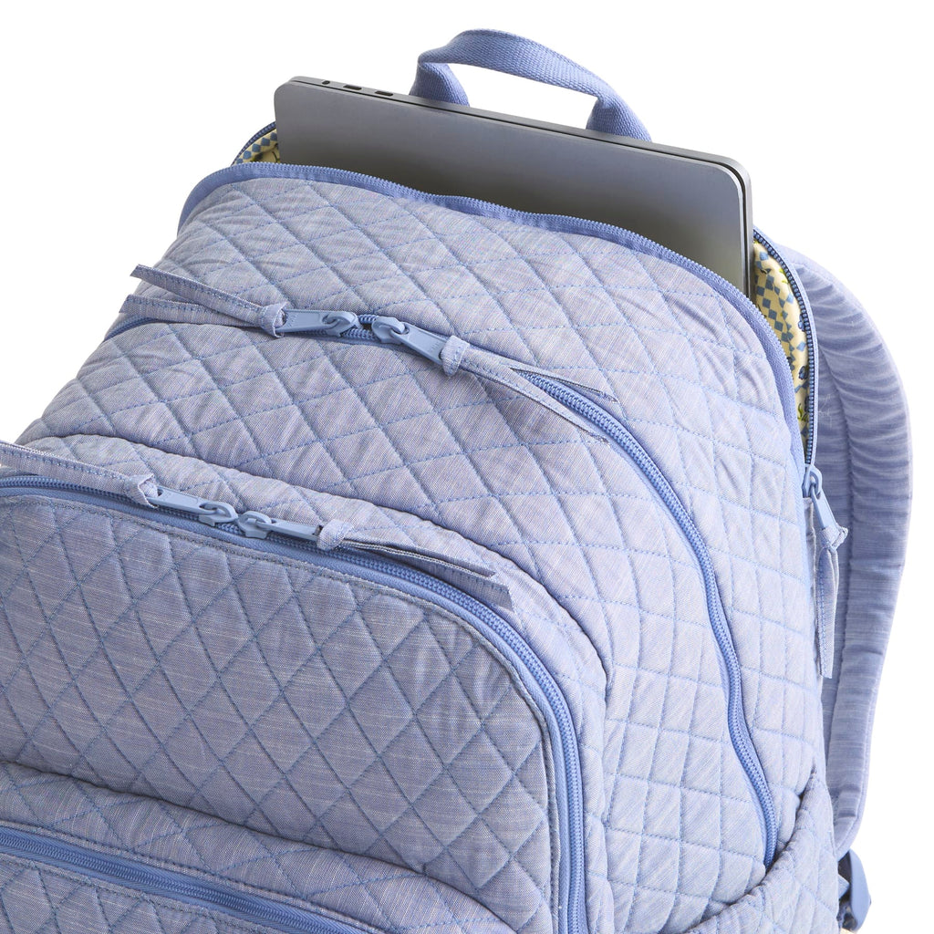 Quilted blue backpack with a laptop inside on a white background